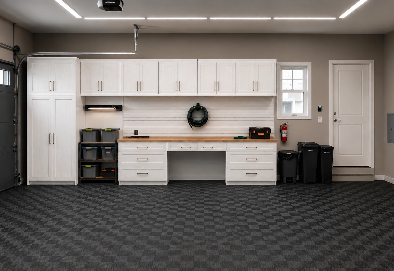 Garage with white cabinetry, a butcher-block workbench and modular charcoal floor tiles.