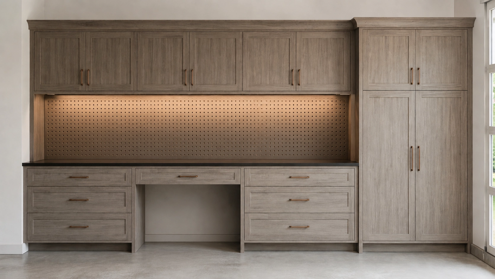 Garage workbench system with a lit pegboard back panel, drawer banks, a dark worktop and a full-height storage cabinet.