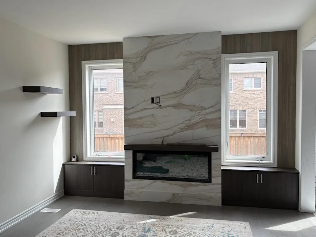 Canadian-Made Custom Cabinetry & Built-In Furniture 5 Canadian-made cabinetry in an Ontario home: a built-in fireplace wall with a stone slab surround, dark flanking base cabinets and floating shelves.