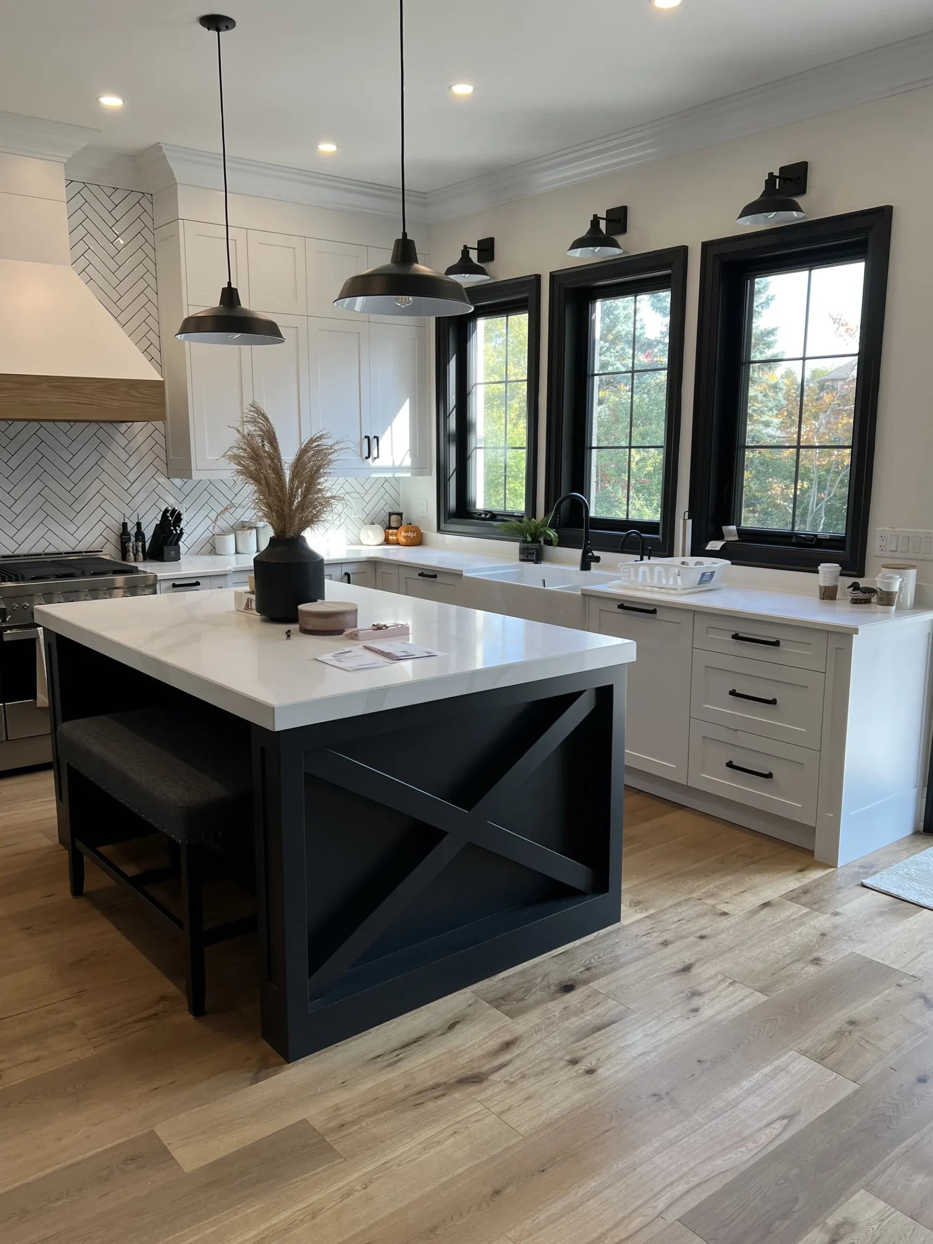 Canadian-Made Custom Cabinetry & Built-In Furniture 3 Canadian-made cabinetry in an Ontario home: a navy X-detail island with bench seating, white perimeter cabinetry and a herringbone tile backsplash.