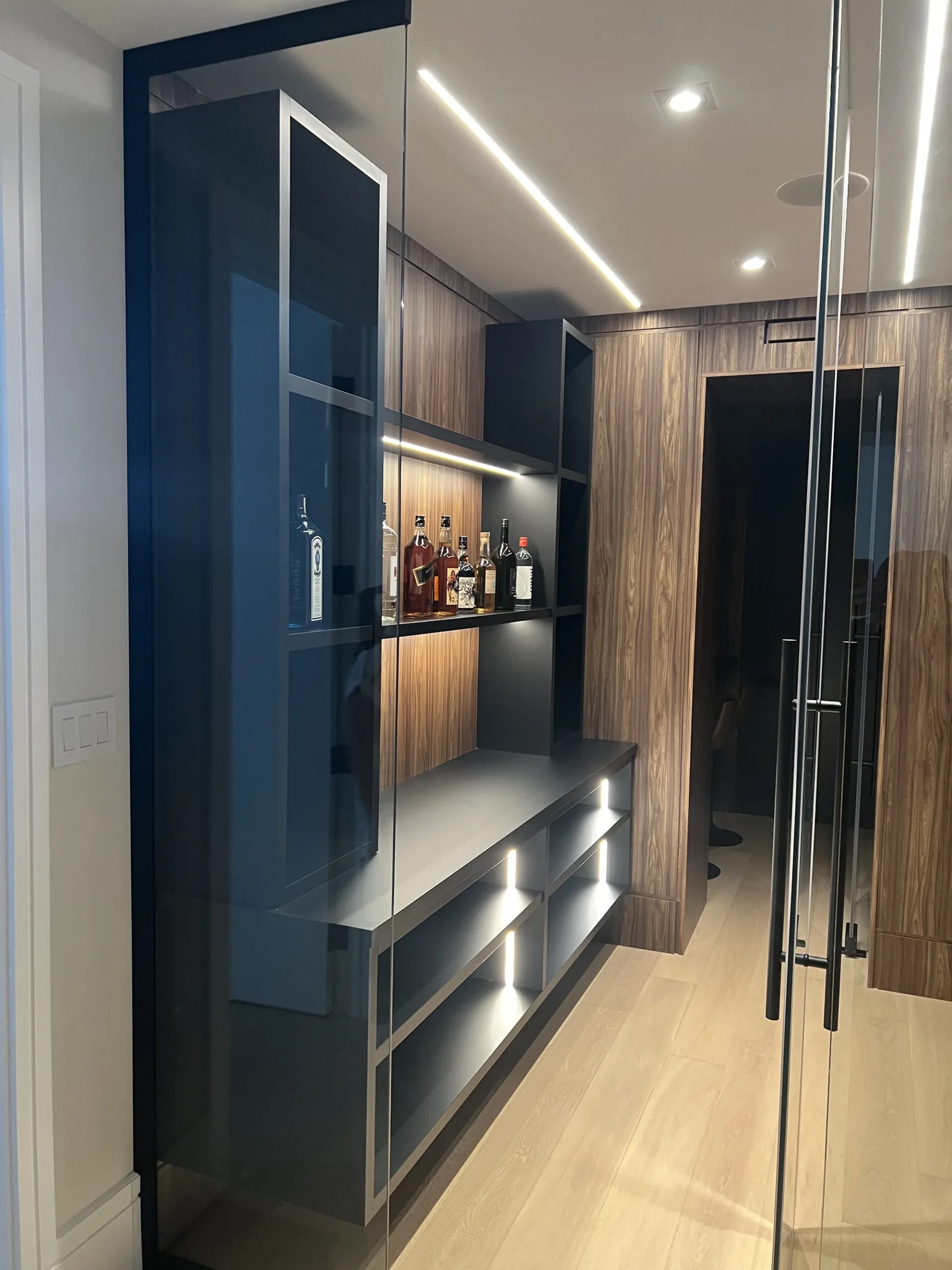 Coffee bar cabinets in an Ontario home: a lit bar shelf with walnut panelling and a floating cabinet run below.