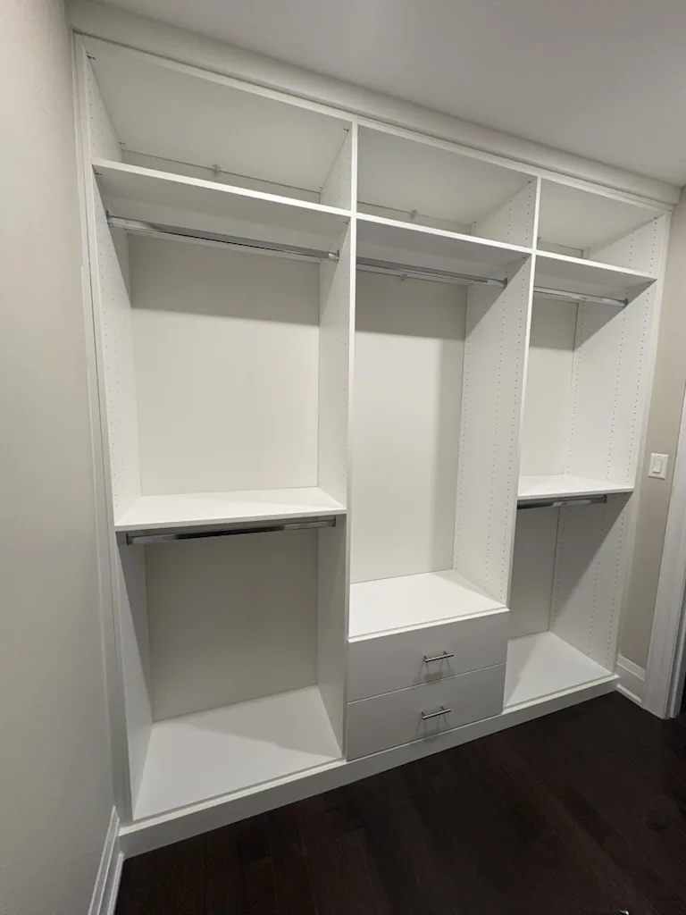 Custom closets in an Ontario home: a three-bay reach-in with full-width upper shelving, double hanging and a low drawer bank.