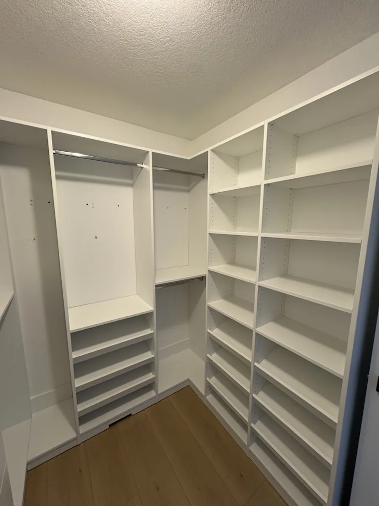 Custom closets in an Ontario home: a walk-in with a full-height angled shoe wall opposite long hanging and open shelving.
