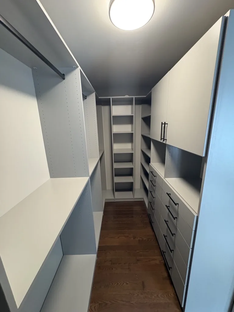 Custom closets in an Ontario home: a two-tone walk-in with a long drawer bank, upper cabinets and high-low hanging down both walls.