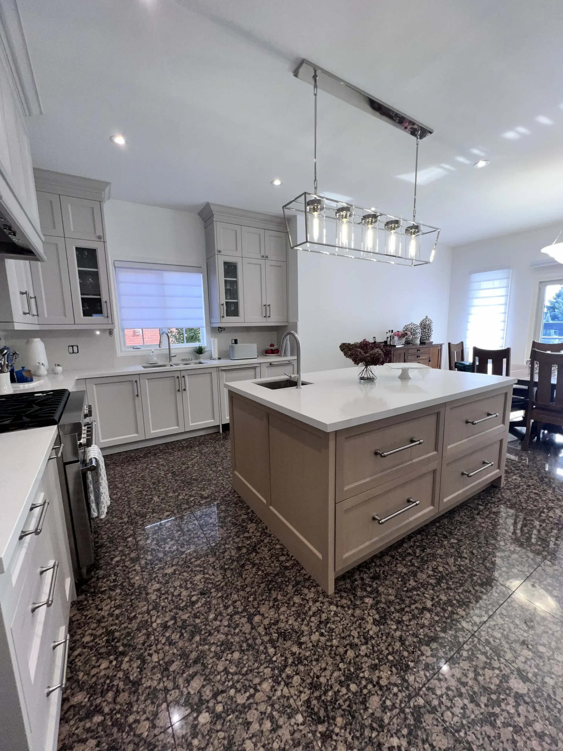Custom kitchen cabinets in an Ontario home: a wood-front island facing a greige shaker range wall with glass-door uppers.