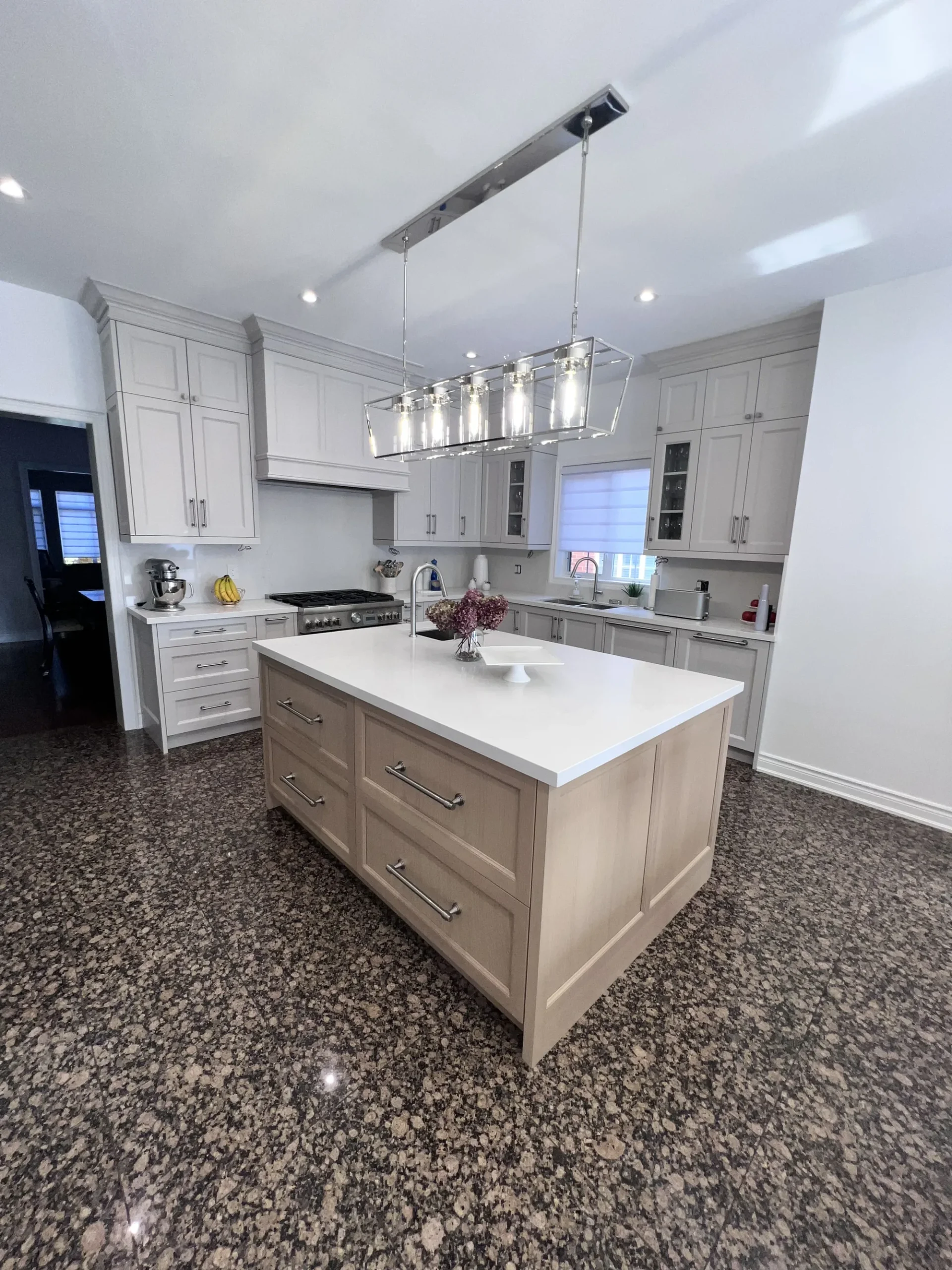 Custom kitchen cabinets in an Ontario home: a wood-front island with deep drawer storage set against greige shaker perimeter cabinetry.