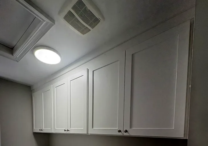 Laundry room cabinets in an Ontario home: a run of white shaker upper cabinets built above the washer and dryer.