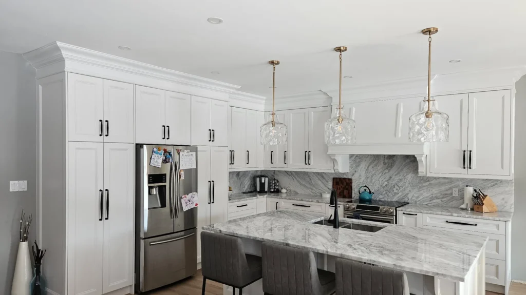 Custom kitchen cabinets in an Ontario home: floor-to-ceiling cabinet towers flanking the fridge, with a seated marble island opposite.